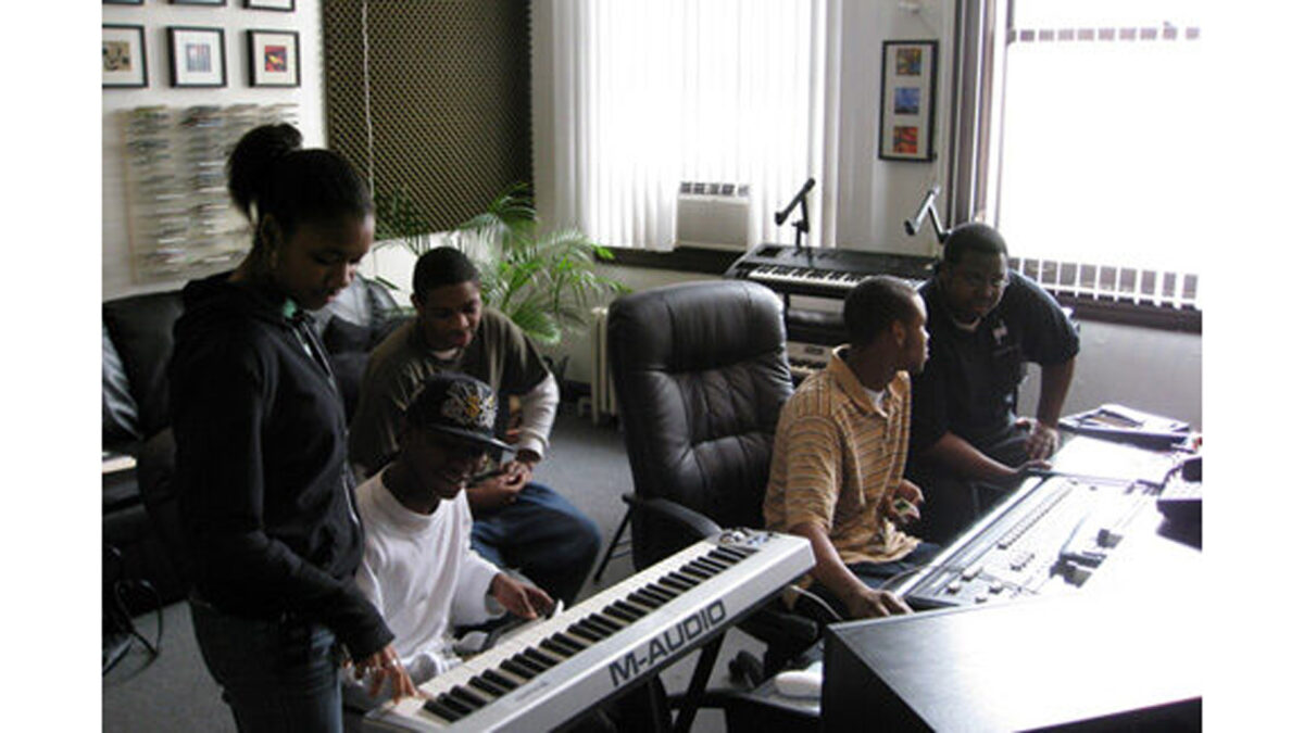 Three teens looking at a piano keyboard and two teens looking at an audio mixer