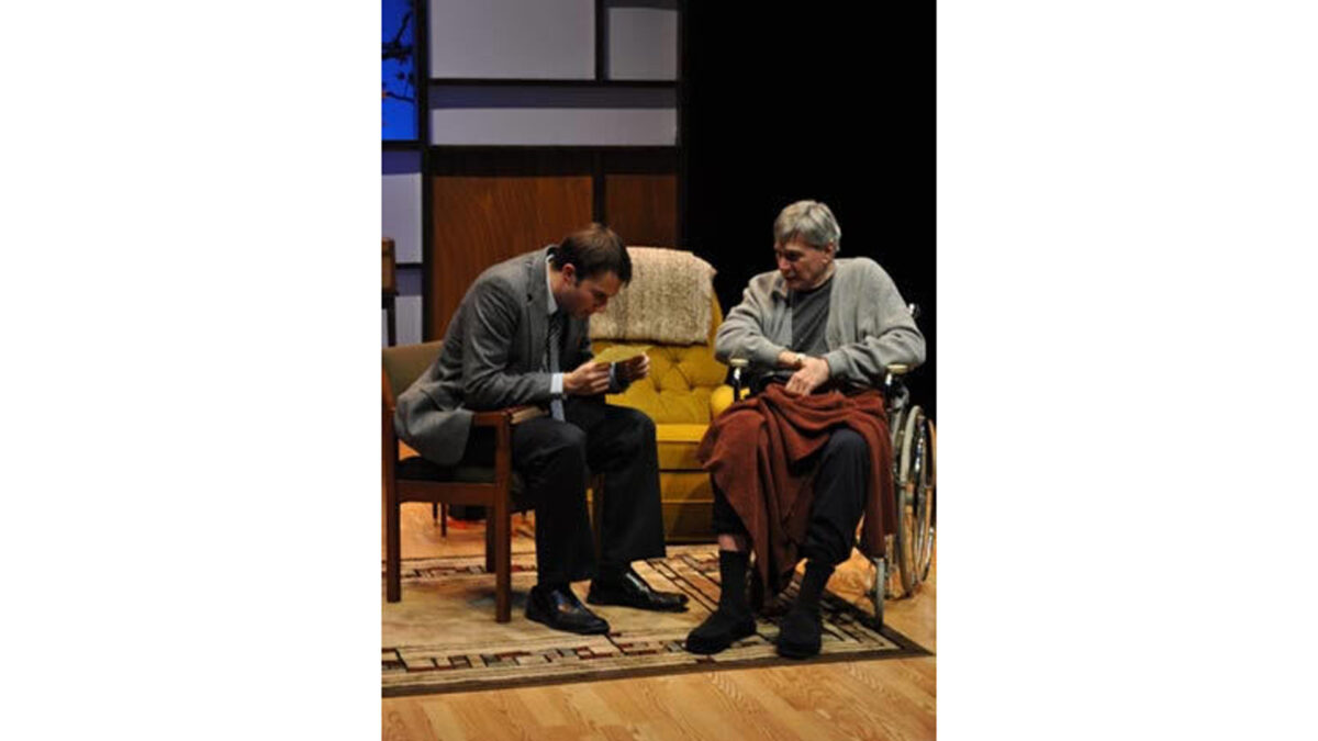 An adult sitting in a chair and an adult in a wheelchair looking at the same piece of paper