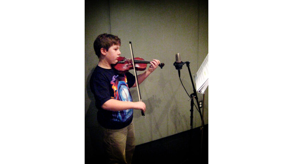 violinist-jimmy_wp A youth playing a violin and looking at sheet music on a music stand in a radio studio