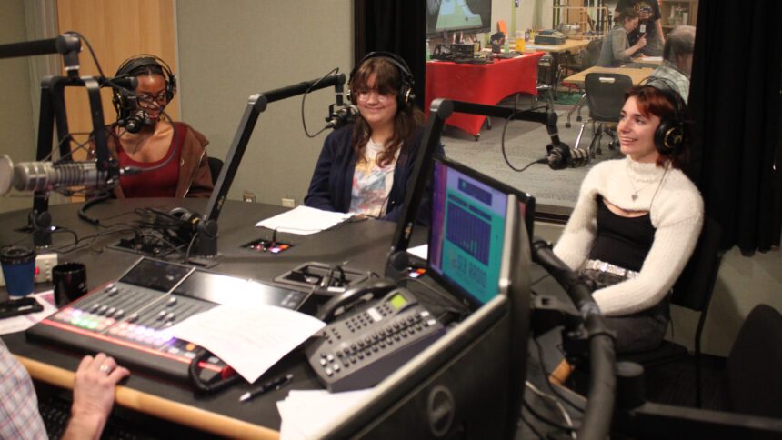 Three teens wearing headphones speaking into microphones being interviewed in a radio studio