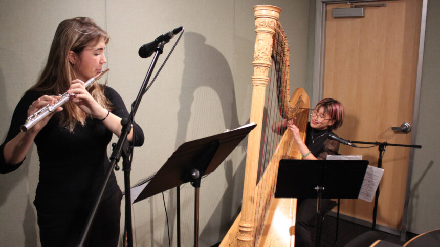 A teen playing flute and a teen playing harp, both looking at sheet music on music stands in a radio studio