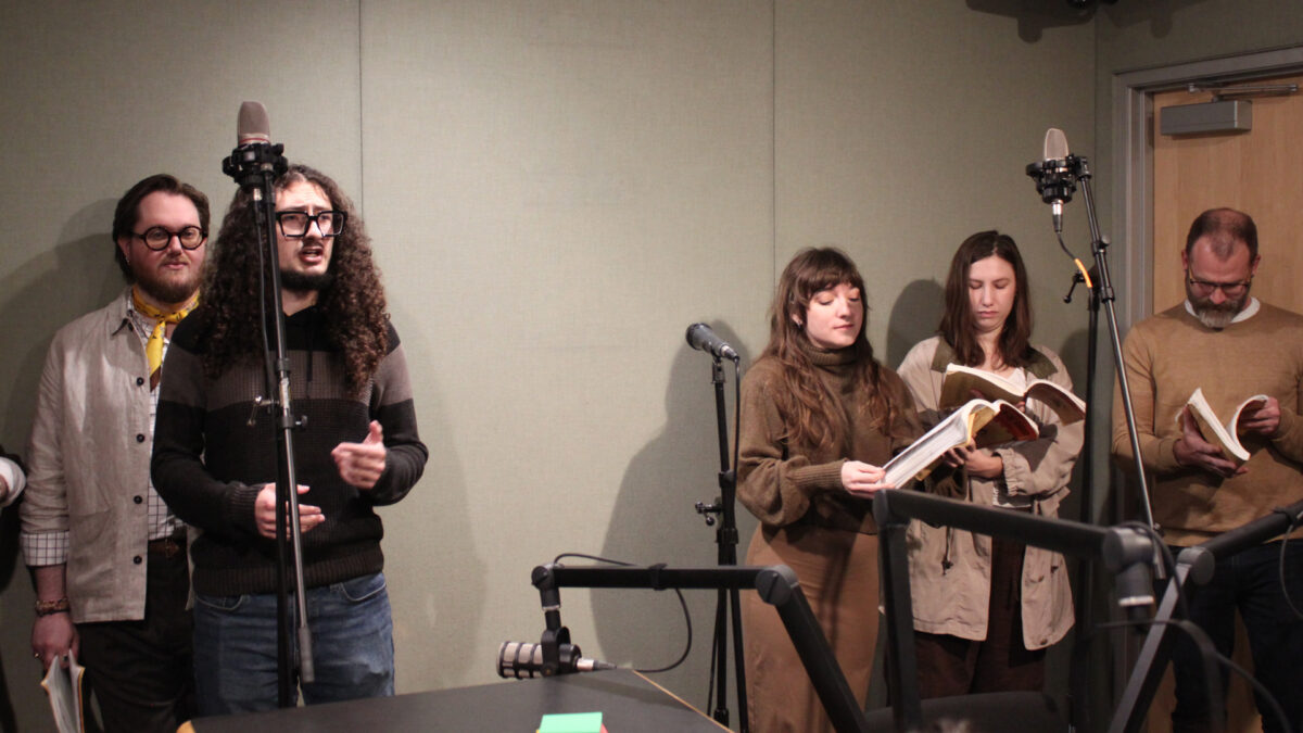 Pittsburgh-Savoyards-3 Five adults standing behind microphones, two singing, in a radio studio