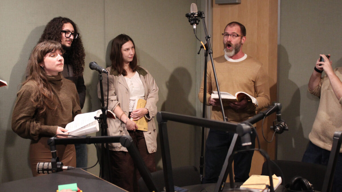 Pittsburgh-Savoyards-4 Four adults standing behind microphones, one singing, in a radio studio