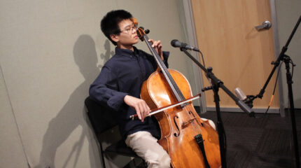 A teen playing cello in a radio studio